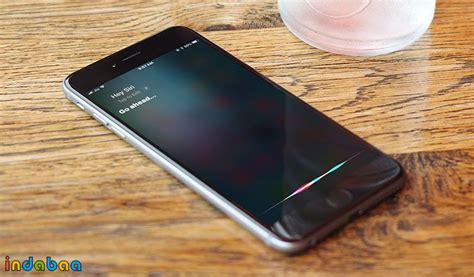 A Cell Phone Sitting On Top Of A Wooden Table Next To A Glass Of Water