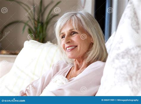Happy Older Woman Sitting On Couch Relaxed And Smiling Stock Image