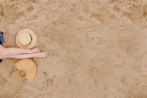 Premium Photo Woman Tanned Legs Straw Hat And Bag On Sand Beach