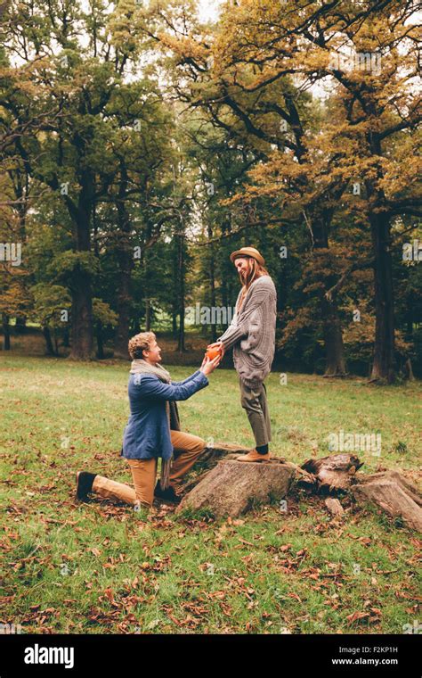 Young Man Kneeling Down And Proposing To His Girlfriend In An Autumnal