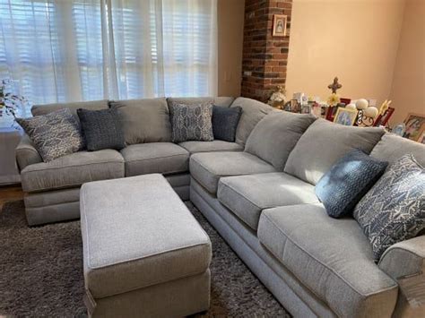 A Living Room With A Sectional Couch And Ottoman