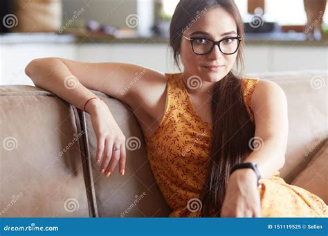 Retrato De La Mujer Sonriente Que Se Sienta En El Sof Lanzamiento Interior Del Estilo Sport