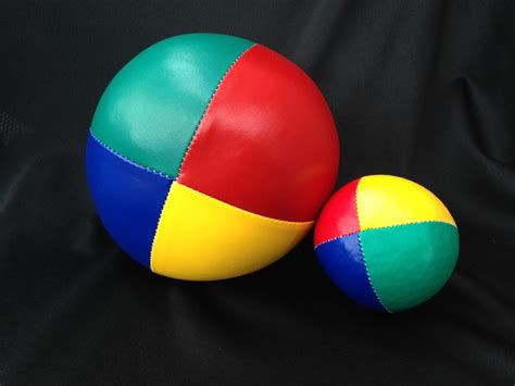 Two Colorful Balls Sitting On Top Of A Black Cloth Covered Floor Next
