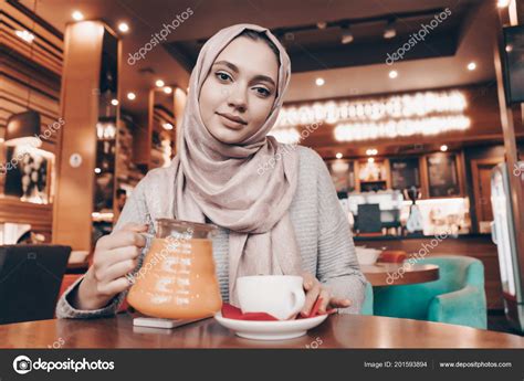 Nice Arab Girl With A Headscarf Sitting In A Cozy Restaurant Drinking Tea And Eating Stock