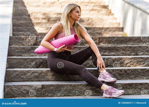 Pensive Fit Blond Girl In Yoga Pants Sitting On Stairs And Looking Away