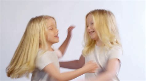 Waist Up Shot Of Vivacious 6 Year Old Blonde Twin Girls Hugging While