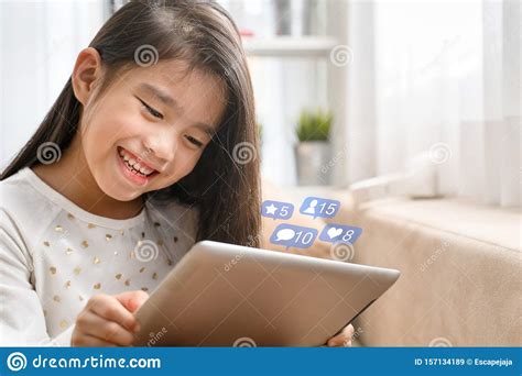 Asian Cute Child Playing Games With A Tablet And Smiling While Sitting