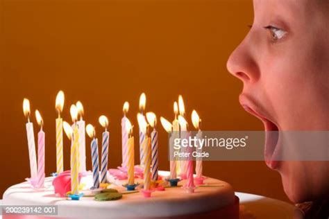 Young Woman Blowing Out Birthday Candles On Cake Closeup Side View