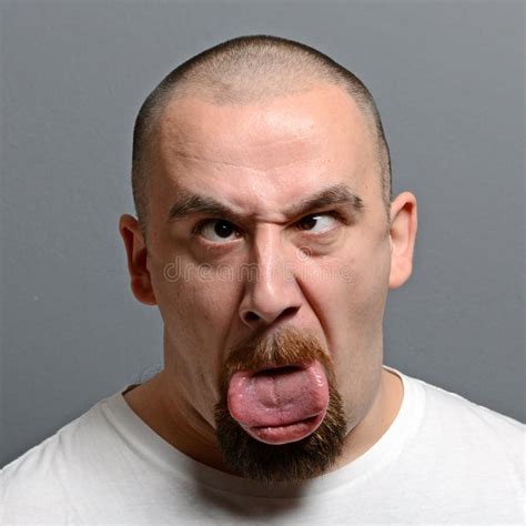 Portrait Of A Man Making Funny Face Against Gray Background Stock Photo