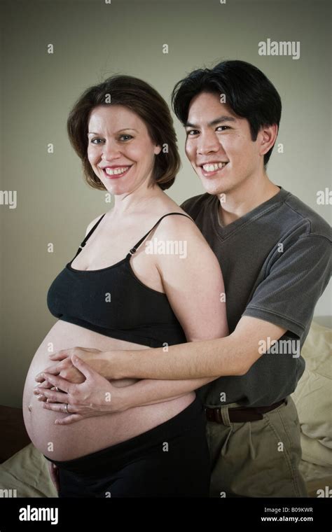 Young Married Couple Asian Man And Pregnant Caucasian Woman Posing