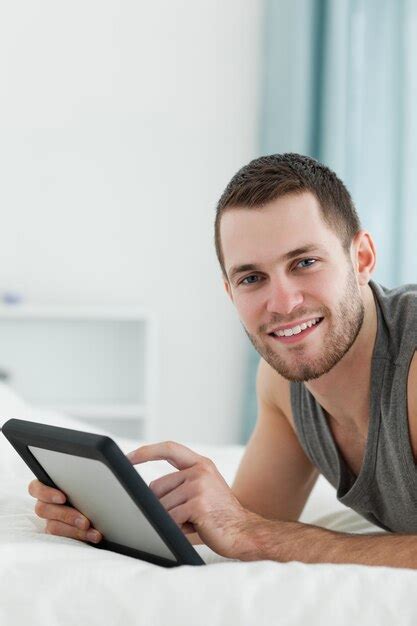 Premium Photo Portrait Of An Attractive Man Using A Tablet Computer While Lying On His Belly