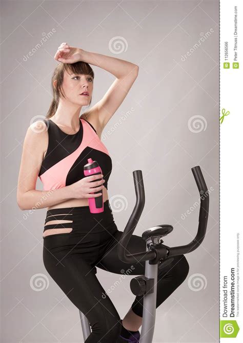 Woman Sitting On An Exercise Bicycle Taking A Break Stock