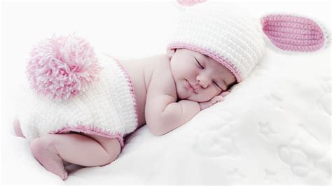 Cute Baby Is Sleeping On White Bed Wearing White Bunny