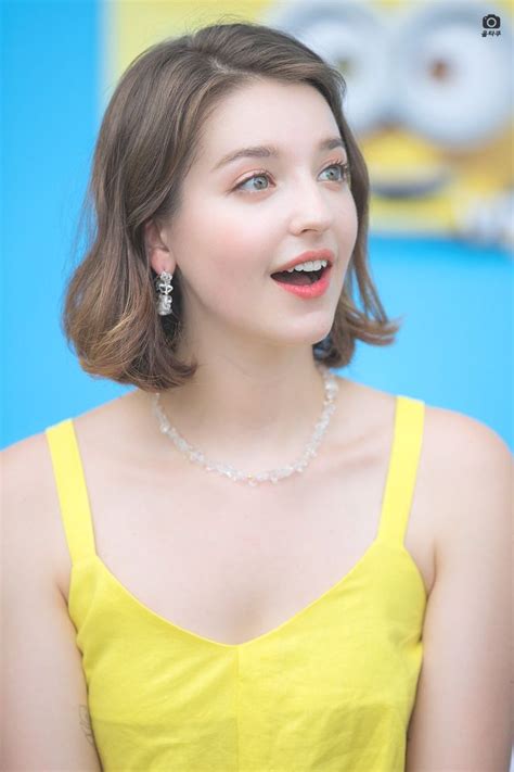 A Woman In A Yellow Dress Is Smiling At The Camera And Has Her Eyes Closed