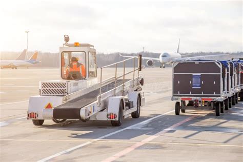 Baggage Carts And A Machine For Loading Luggage Into The Cargo Hold Of