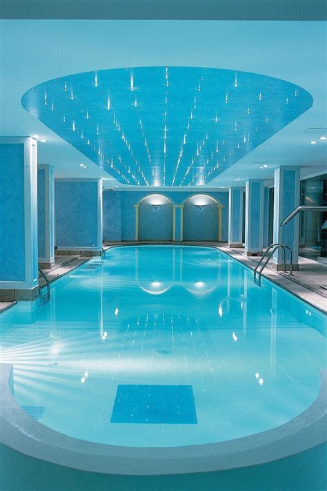 A Large Indoor Swimming Pool With Blue Walls And Water Features In The