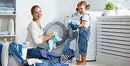 family mother and child girl in laundry room near washing machine ...