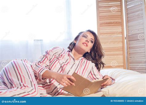 Girl In Pajamas Lying On The Bed And Reading A Book Stock Image Image