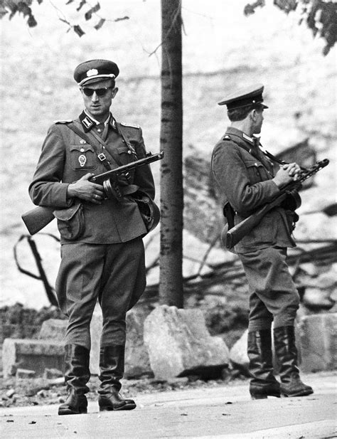 soldiers from the east german national people s army man an unfinished part of the berlin wall