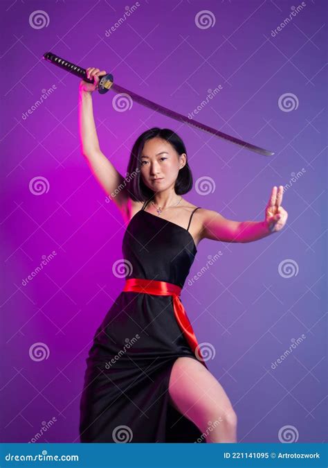 slender asian woman in a black dress with a katana in her hand image of a samurai on a neon