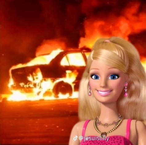 A Barbie Doll Standing In Front Of A Burning Car