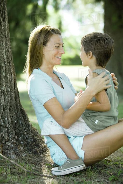 Mother And Son Outdoors Boy Sitting On Woman S Lap Stock Photo