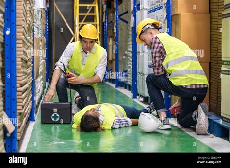 Warehouse Worker Do First Aid To His Colleague Lying Down On Warehouse