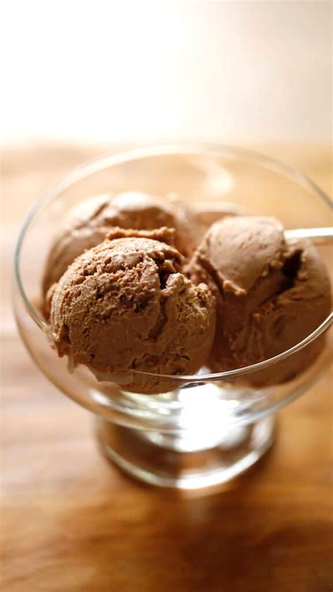 Three Scoops Of Chocolate Ice Cream In A Glass Bowl With Mint Sprigs