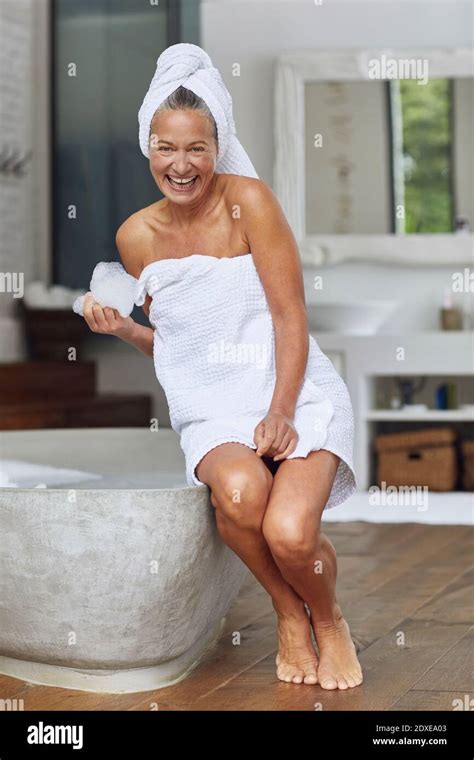 Happy Mature Woman Playing With Bubbles While Sitting At Edge Of