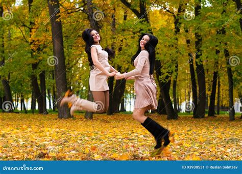 Two Beautiful Brunette Girls Jumping On Background Autumn Park Stock