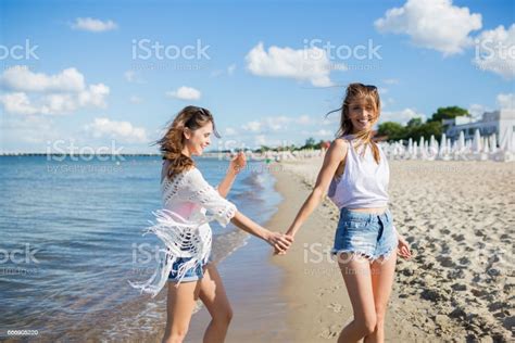 Hübsche Mädchen Zu Fuß Am Strand An Hand Mit Ihrer Freundin Stockfoto