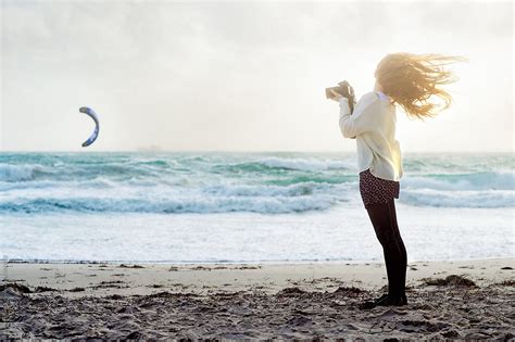 Teenage Girl Taking Photos At The Beach On A Windy Day By Stocksy