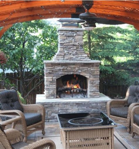 An Outdoor Fireplace With Wicker Chairs Around It