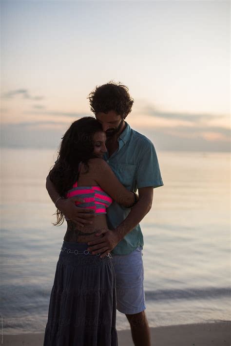 Young Couple Hugging At The Beach At Sunset Del Colaborador De Stocksy Mosuno Stocksy