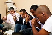 A Group Of Men Praying Together With An Open Bible Stock Photos ...