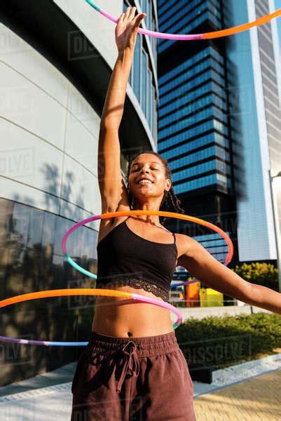 Generation Z Woman Performing Hula Hoop Dance With Rings In Downtown