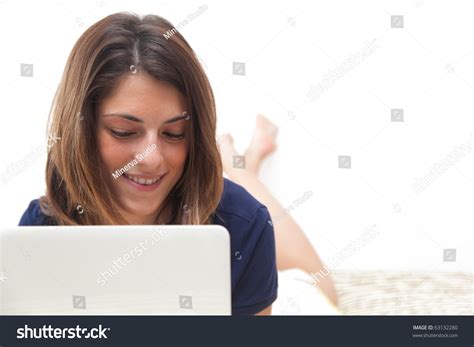 Barefoot Beautiful Girl Relaxing On The Bed With Her Laptop Stockfoto