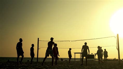 People play volleyball on the beach at sunset. Friends ...