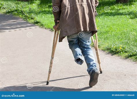 The One Legged Disabled Person Walks In Park On Crutches Stock Photo