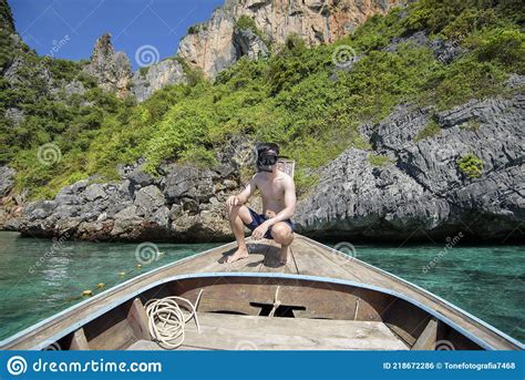 active man on thai traditional longtail boat is ready to snorkel and dive phi phi islands