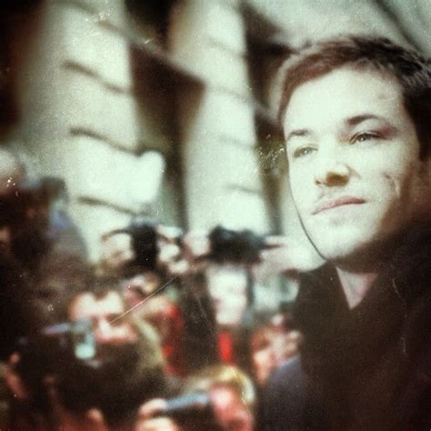 A Young Man With Headphones On Standing In Front Of A Group Of People Taking Pictures