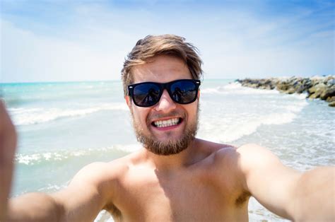 Handsome Hipster Man On Beach Wearing Sunglasses Smiling Taking Selfie Enjoying Time At