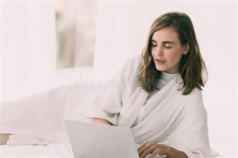 Caucasian Woman Laying And Playing With Laptop On Her Bed Stock Photo