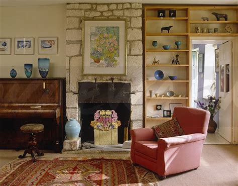Love the way it stands out so brightly among the white walls, floorboards and lamp. Image: Pink armchair in front of simple wooden shelves in ...