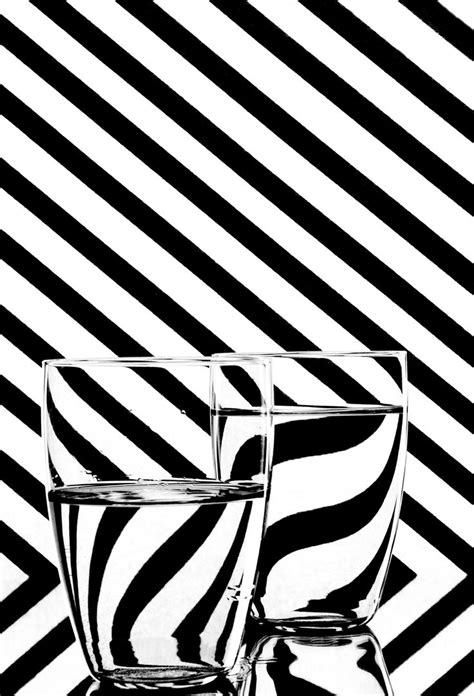 black and white photograph of two glasses in front of a striped wall with diagonal stripes