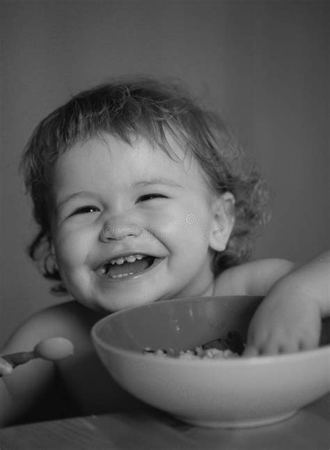 Funny Baby Eating Food Himself With A Spoon On Kitchen Smiling Baby