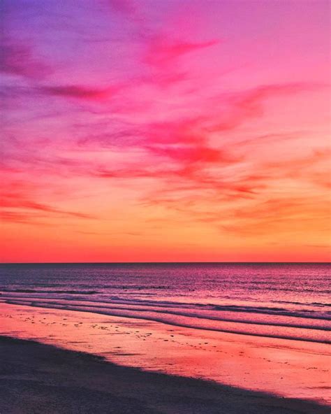 the sun is setting over the ocean with pink and purple clouds