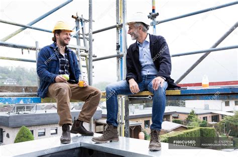 Architect And Construction Worker Talking While Sitting At Construction