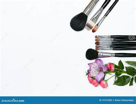 Composition With Makeup Cosmetics Brushes And Flowers On White