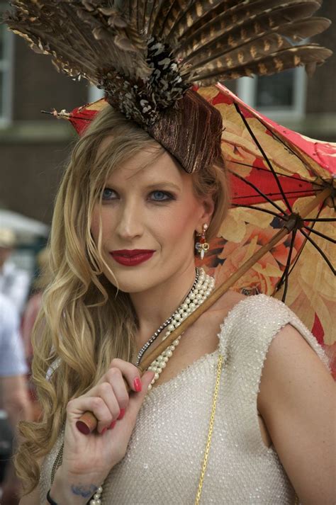 a woman wearing a feather hat and holding an umbrella